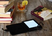 El eterno debate entre los lectores: libros en digital o en papel E-reader sobre una mesa con libros en papel